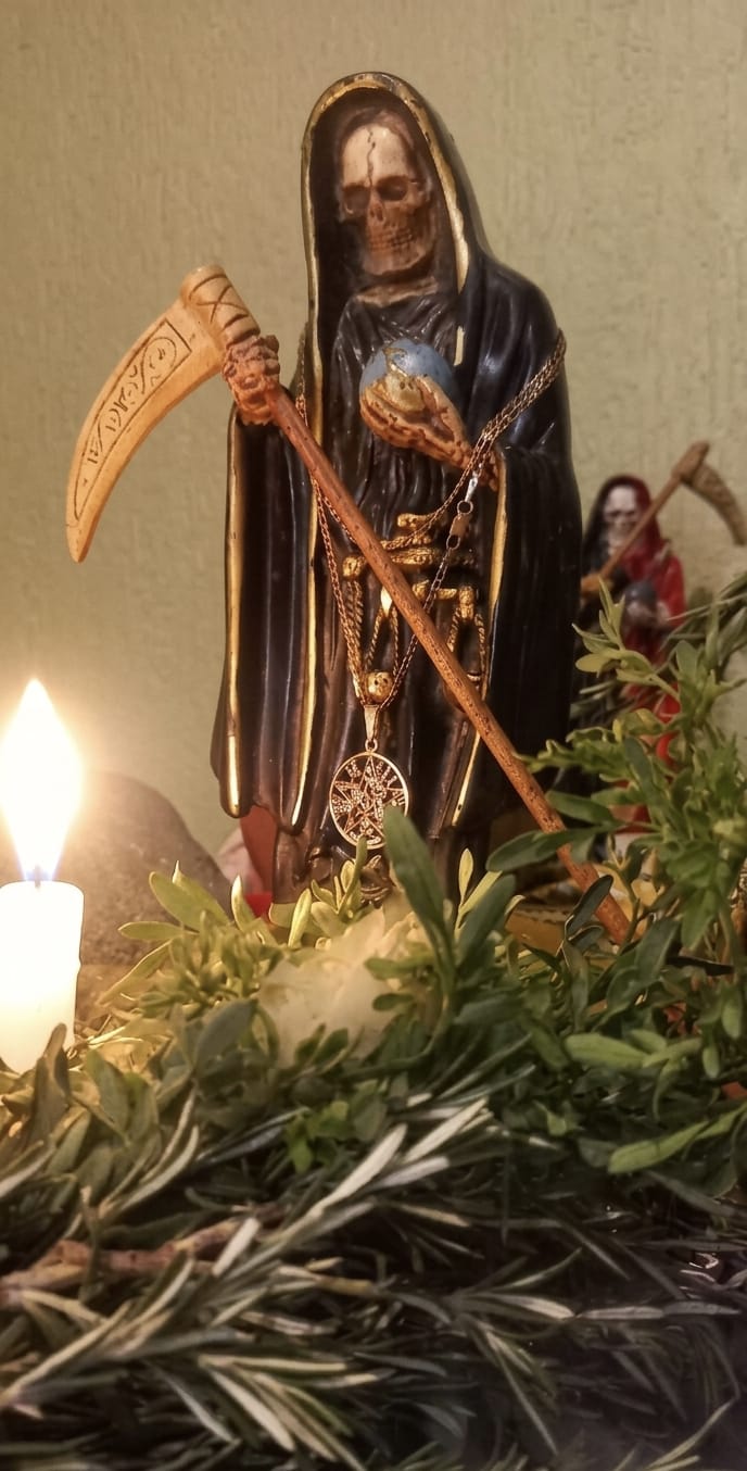 Santa Muerte con hierbas de limpia y vela encendida en el altar