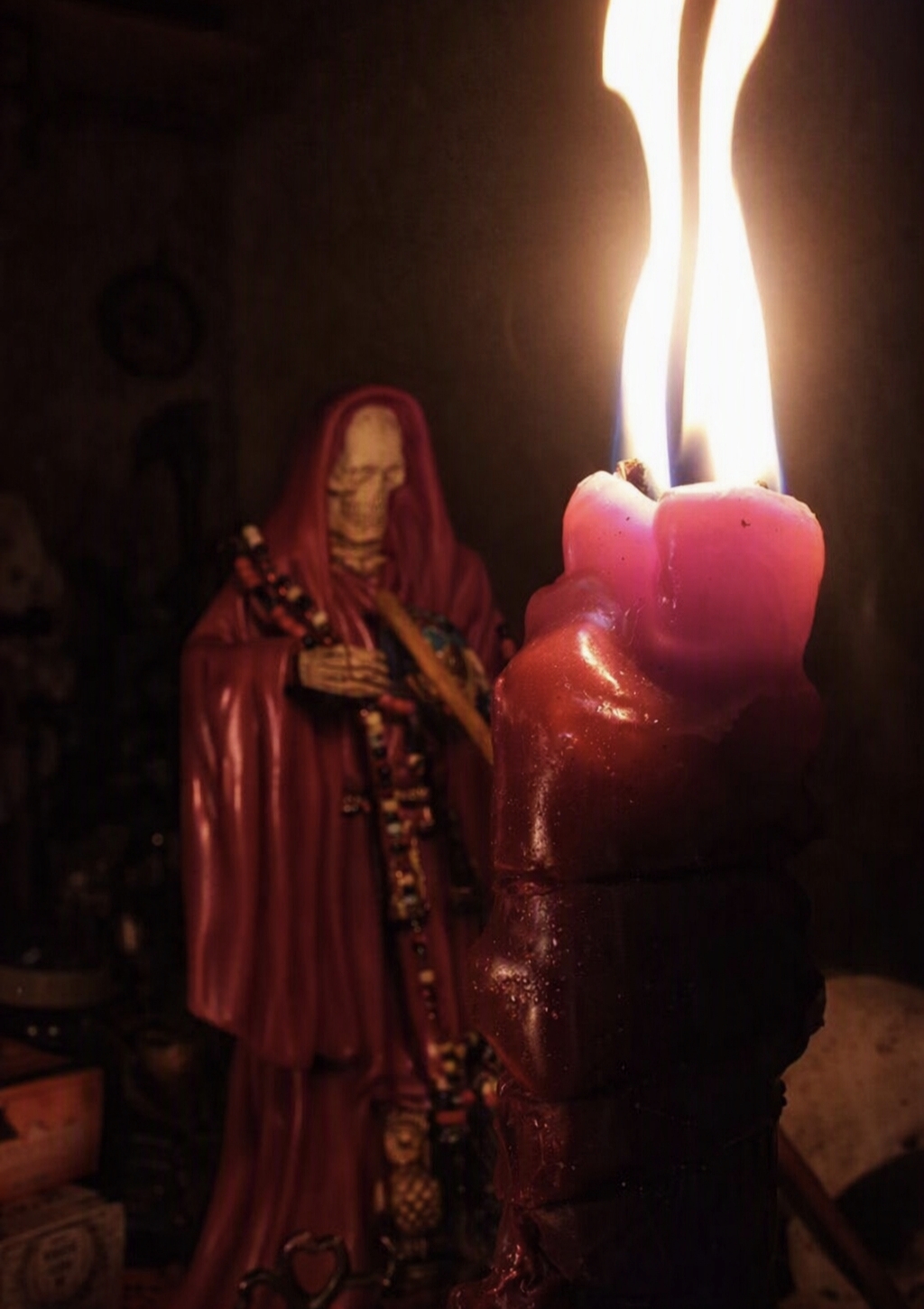 Vela roja encendida frente a la Santa Muerte en el altar
